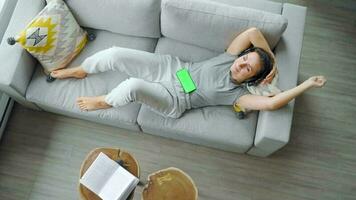 avslappnad kvinna i hörlurar med smartphone med grön mock-up skärm video