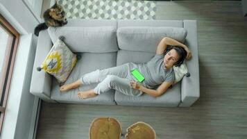 rilassato donna nel cuffie con smartphone con verde modello schermo video