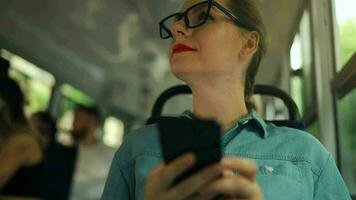 Publique transport. femme dans des lunettes dans tram en utilisant téléphone intelligent. video