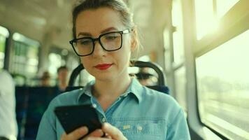 público transporte. mujer en lentes en tranvía utilizando teléfono inteligente lento movimiento video