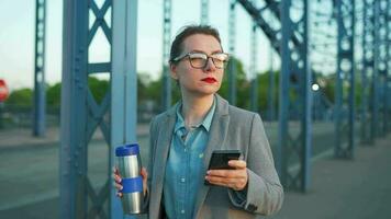 mujer en un abrigo, caminando alrededor el ciudad en el temprano mañana, Bebiendo café video