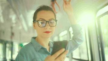 Publique transport. femme dans des lunettes dans tram en utilisant téléphone intelligent, lent mouvement video