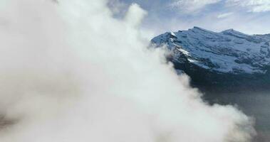 Aerial view of the clouds, rocky mountains are visible through them. video