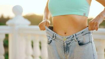 Woman enjoy weight loss at home. Female in old jeans after successful diet. video