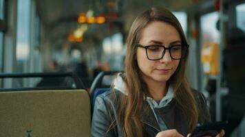 Public transport. Woman in glasses in tram using smartphone video