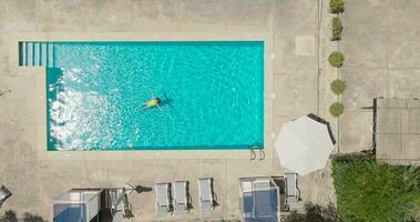 parte superior abajo ver de un mujer en un amarillo traje de baño acostado en su espalda en el piscina. video