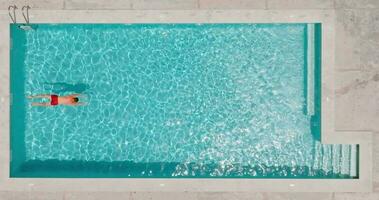 Aerial view as a man dives into the pool and swims. Slow motion video