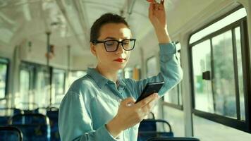 Publique transport. femme dans des lunettes dans tram en utilisant téléphone intelligent. lent mouvement video