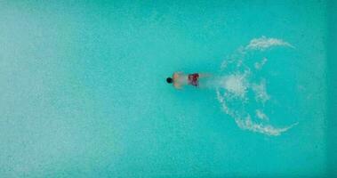 Antenne Aussicht wie ein Mann Tauchgänge in das Schwimmbad und schwimmt. schleppend Bewegung video