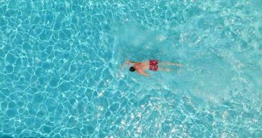 aéreo ver de un hombre en rojo pantalones cortos nadando en el piscina. video