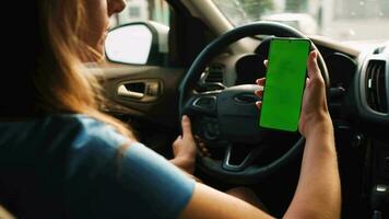 femelle chauffeur en utilisant une téléphone intelligent à l'intérieur le auto. chromakey téléphone intelligent avec vert video