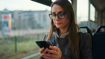 Public transport. Woman in glasses in tram using smartphone, slow motion video