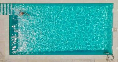 aéreo ver de un mujer en azul traje de baño nadando en el piscina. verano estilo de vida video