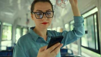 público transporte. mujer en lentes en tranvía utilizando teléfono inteligente video