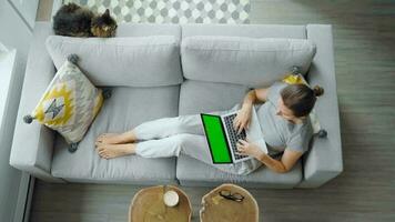 Overhead shot of woman using laptop with green mock-up screen video