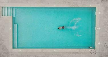 Aerial view as a man dives into the pool and swims. Slow motion video