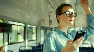 Öffentlichkeit Transport. Frau im Brille im Straßenbahn mit Smartphone. schleppend Bewegung video