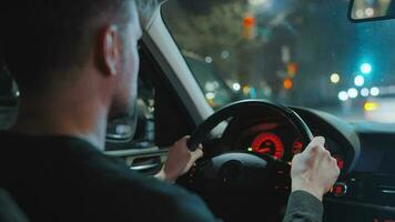 hombre conducción coche mediante el calles de noche ciudad. video