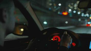 hombre conducción coche mediante el calles de noche ciudad. video