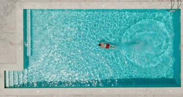 Aerial view as a man dives into the pool and swims. video