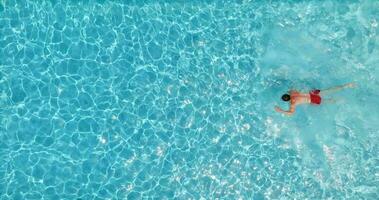 Aerial view of a man in red shorts swimming in the pool. video
