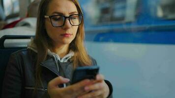 Public transport. Woman in glasses in tram using smartphone video