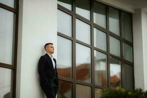 portrait of a young guy groom in a dark wool suit photo