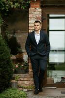 portrait of a young guy groom in a dark wool suit photo