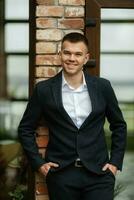 portrait of a young guy groom in a dark wool suit photo