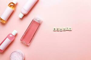 Flat lay word beauty from wooden letters on a pink background. Bottles mockup. spa jars photo