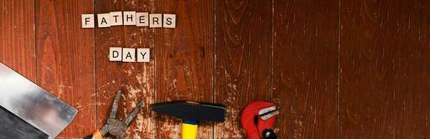 Banner Flat lay happy father's day lined with letters. Building tools on a wooden background. Repair and construction photo