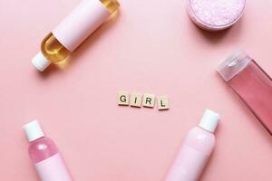 Flat lay word girl from wooden letters on a pink background. Bottles mockup. Spa jars. Girl care. beauty routine photo