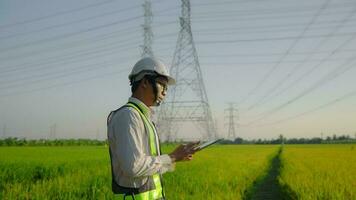 Electrical engineer wearing uniform holding tablet working near high voltage pylon video