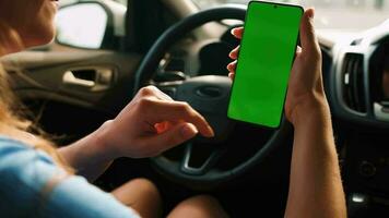 vrouw bestuurder gebruik makend van een smartphone binnen de auto. Chroma sleutel smartphone met groen video