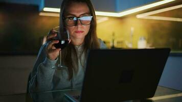 Woman is sitting in the kitchen and working on a laptop at night video