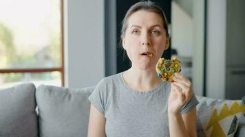 Hungry woman biting and chewing colourful chip cookie close-up video