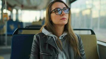 Publique transport. femme dans des lunettes dans tram en utilisant téléphone intelligent, lent mouvement video