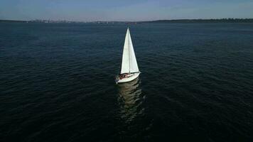 aérien orbite vue de une bateau voile le long de le côte à le coucher du soleil. video