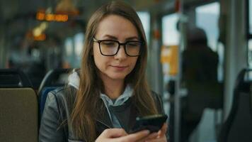 público transporte. mujer en lentes en tranvía utilizando teléfono inteligente video