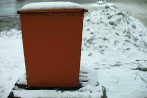 Steel tank. Dumpster. Place to store sand on highway. Orange object in winter on road. photo