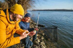 Father and son are fishing on sunny winter day photo