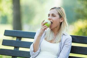 un mujer comiendo un manzana en el parque foto