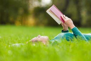 un mujer gasto hora al aire libre y leyendo un libro foto