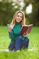 un mujer gasto hora al aire libre y leyendo un libro foto