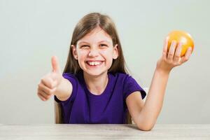 un niña comiendo un naranja foto