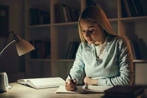 Young blonde woman studying at night photo