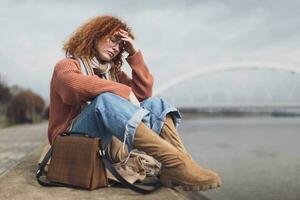 Upset young woman with freckles and curly ginger hair outdoors photo