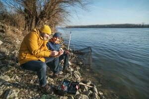 Father and son are fishing on sunny winter day photo