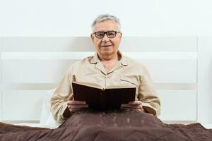 un mayor hombre en su dormitorio con un libro foto