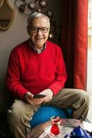 A senior man in a red sweater relaxing photo